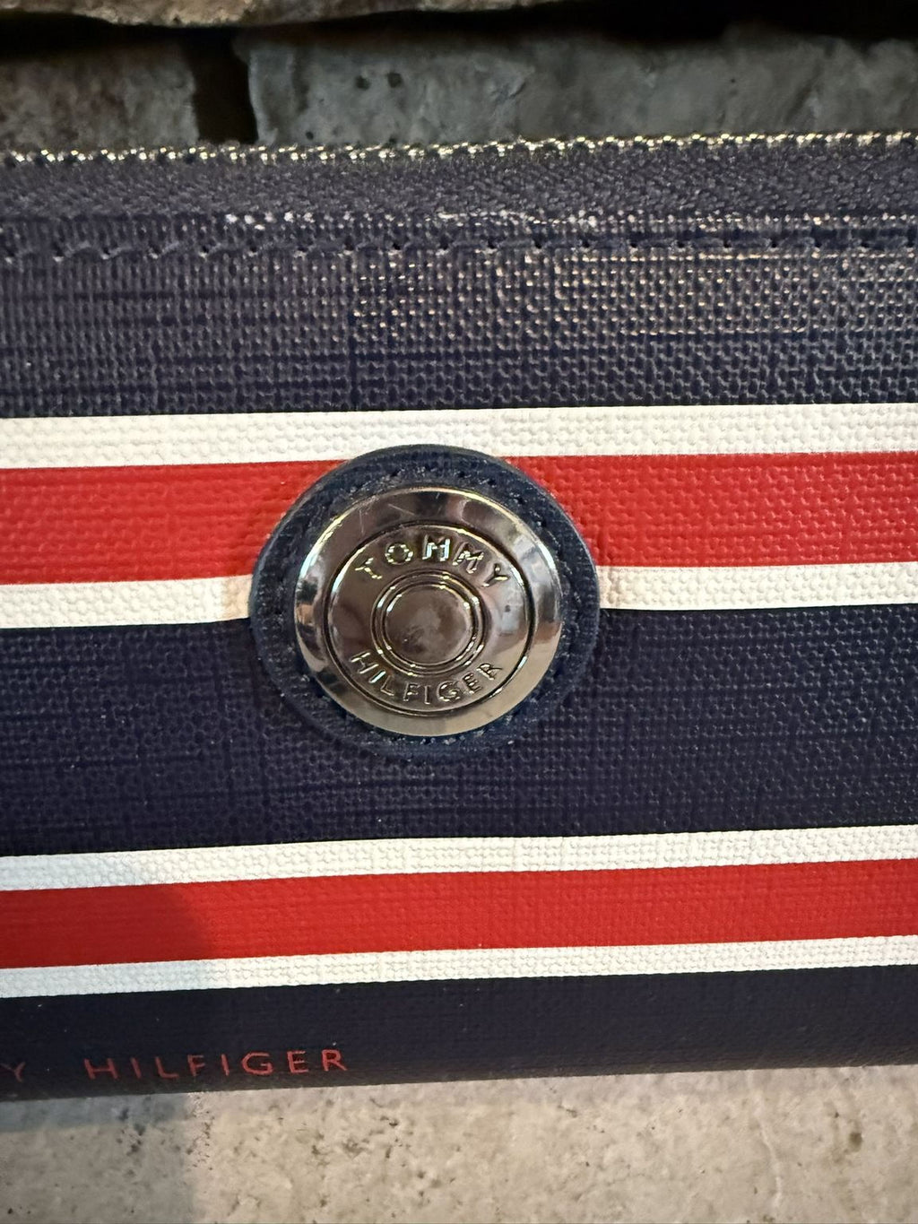 A close-up view of a navy blue and red striped purse with a metal buckle.