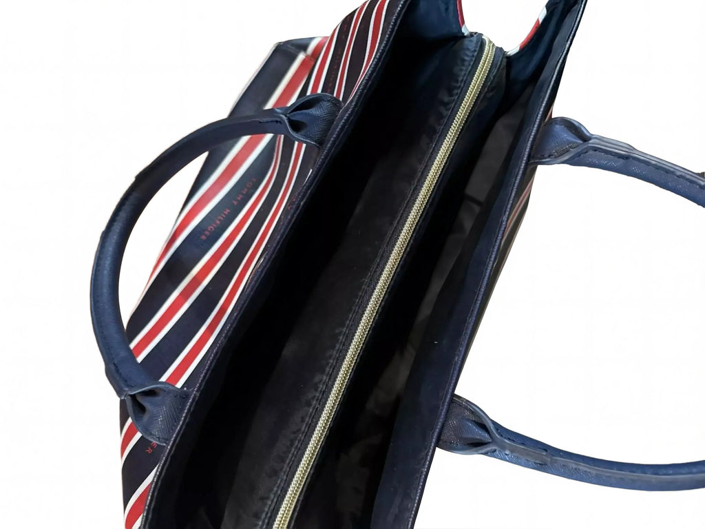 A striped tote bag with a black interior and red and white stripes, placed on a wooden floor.