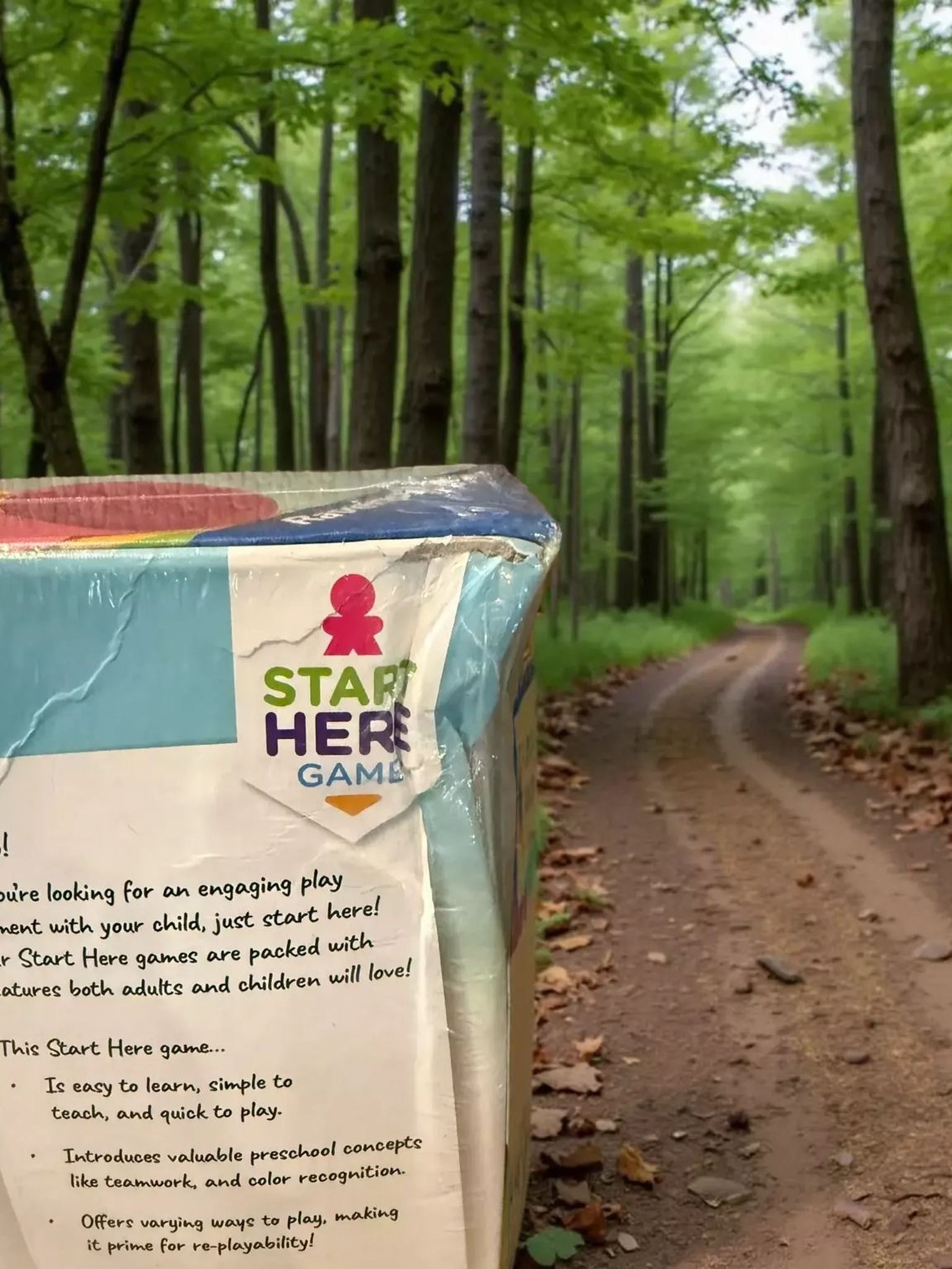 a colorful box of educational games placed on a dirt path in a forested area.