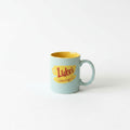A light blue mug with a yellow interior, featuring the text "Luke's Galmore girls" in a stylized font.