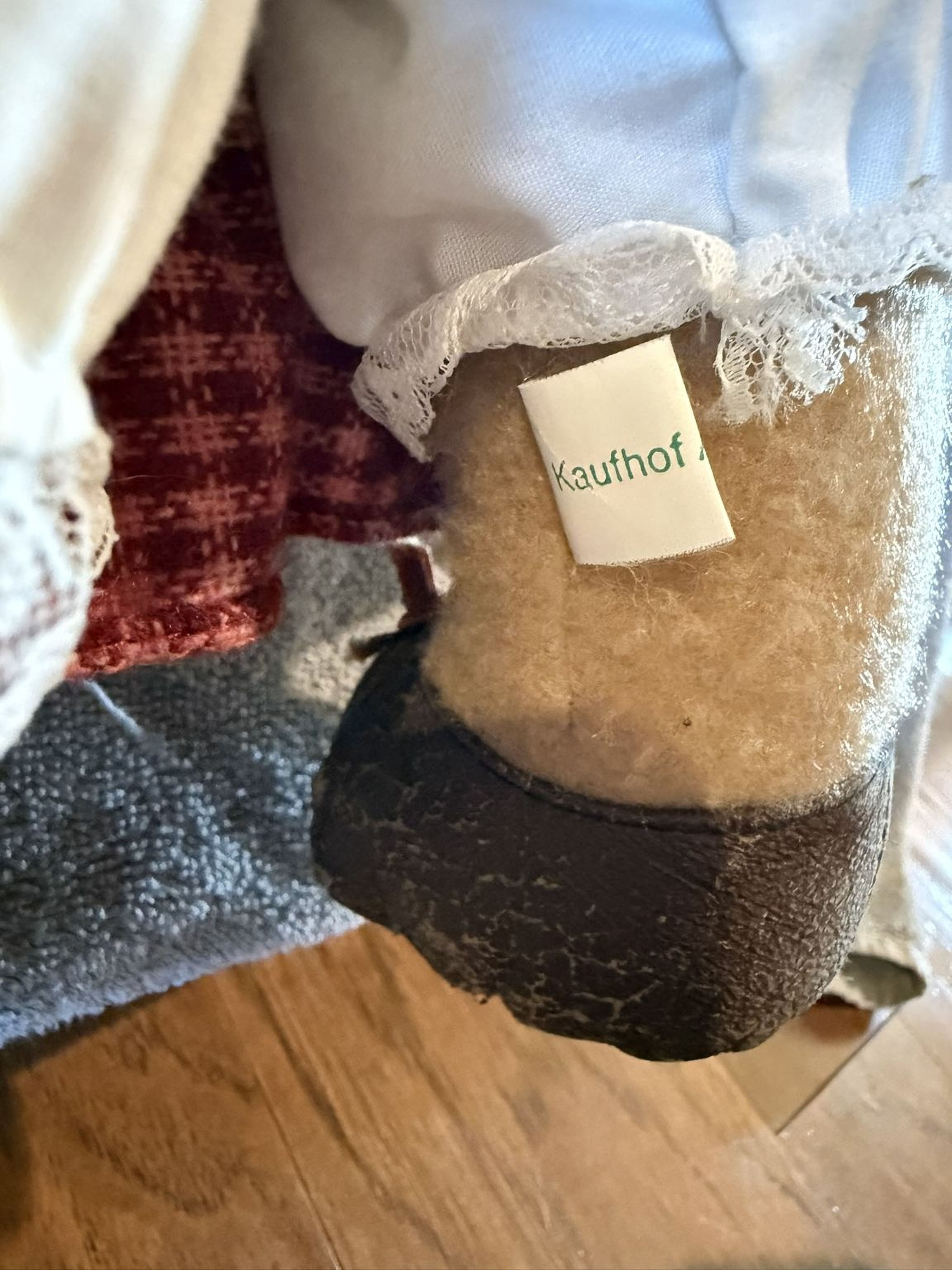 A close-up view of a pair of brown boots with a lace trim, featuring a label that reads "Kauhof" on the heel.