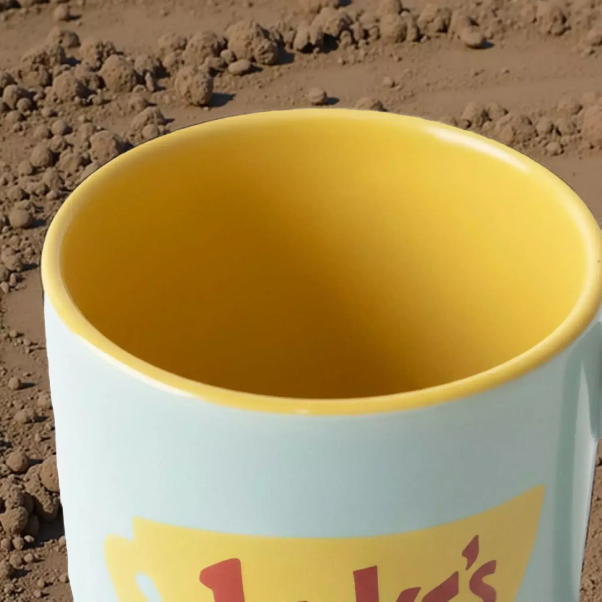 A close-up view of a yellow and blue mug with a red and yellow logo on it.